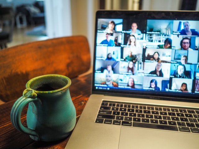 a coffee mug next to a digital conference on a laptop