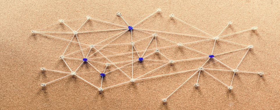 Blue and white pins connected by string on a cork board to illustrate a network