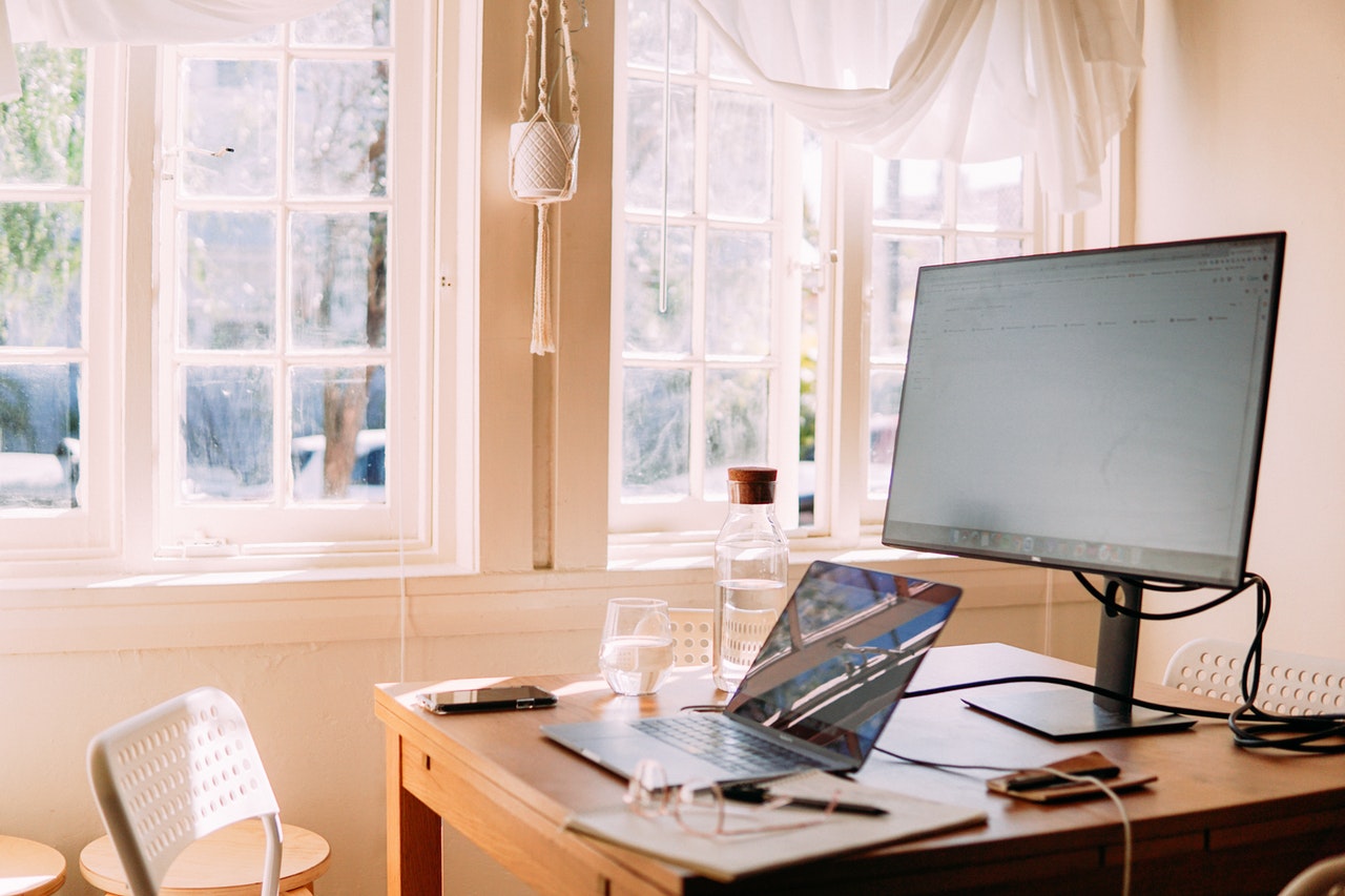 A laptop and a computer monitor on a wooden desk